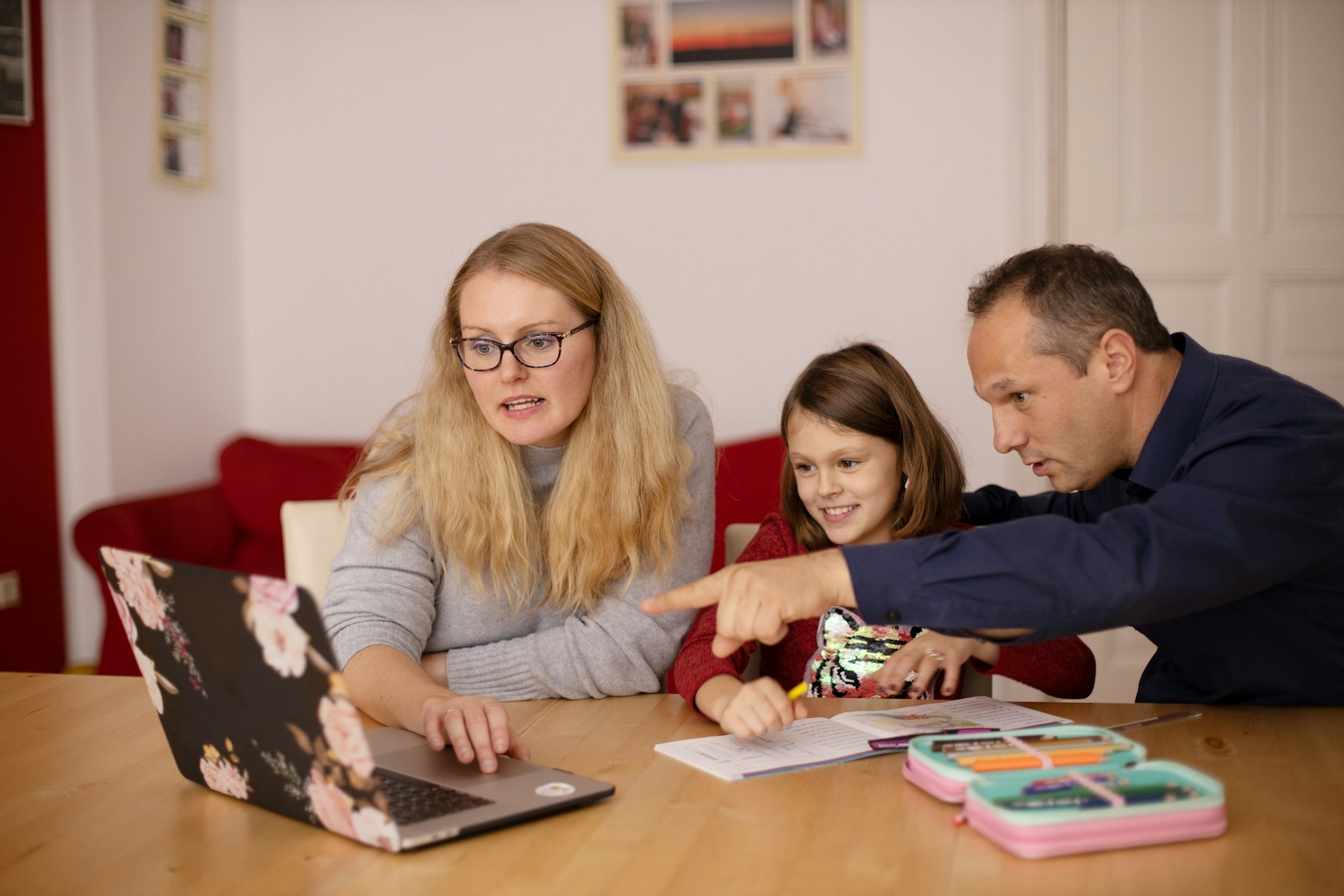 Parents helping their daughter with schoolwork at a laptop at home