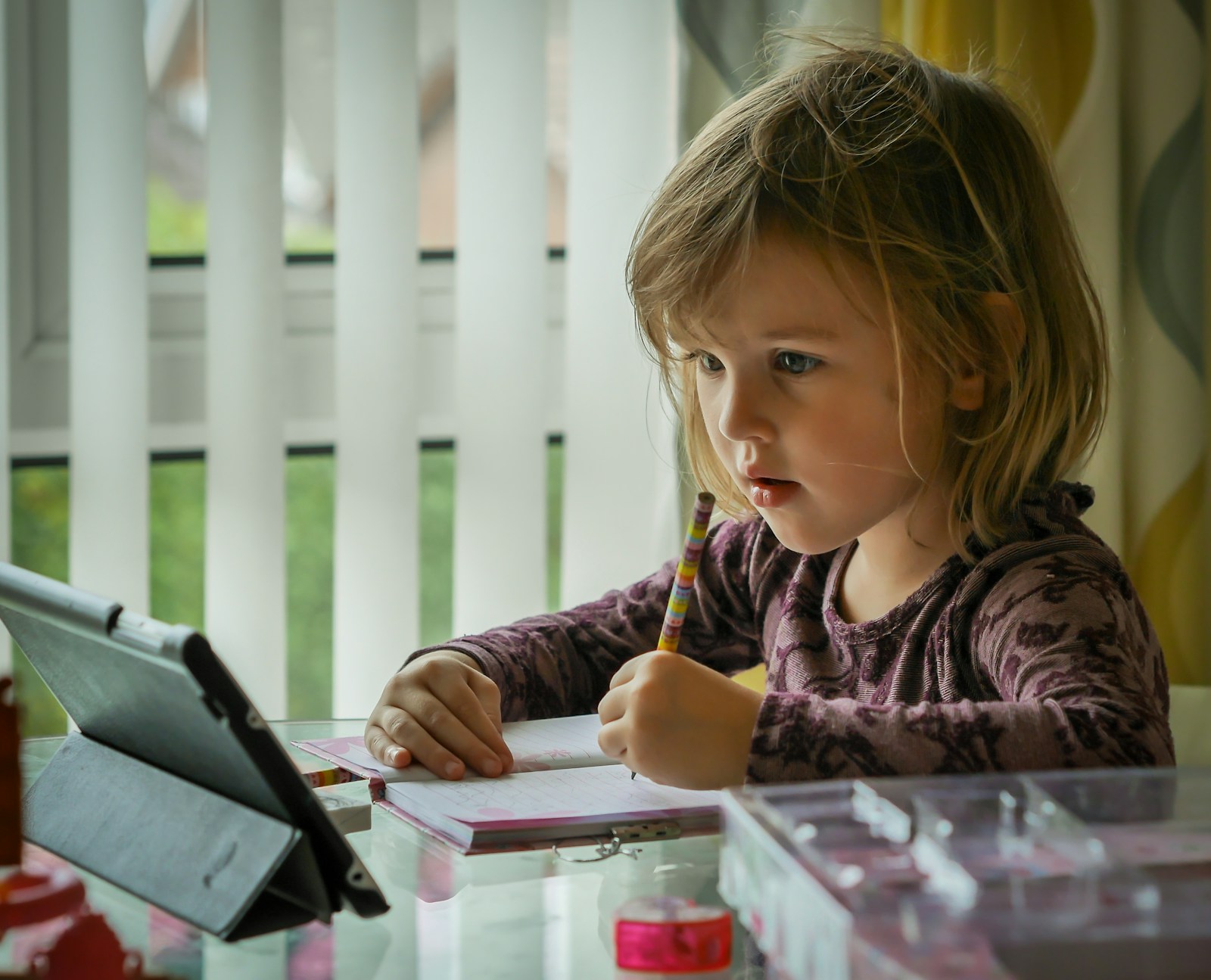 A young girl following an online lesson on a tablet at home